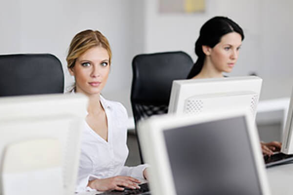 two women sitting at a shared desk 